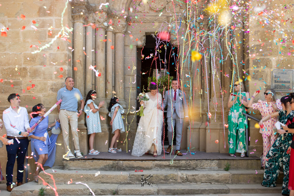 Pareja de novios recien casados saliendo de la iglesia. Confeti. Fotografo de bodas.